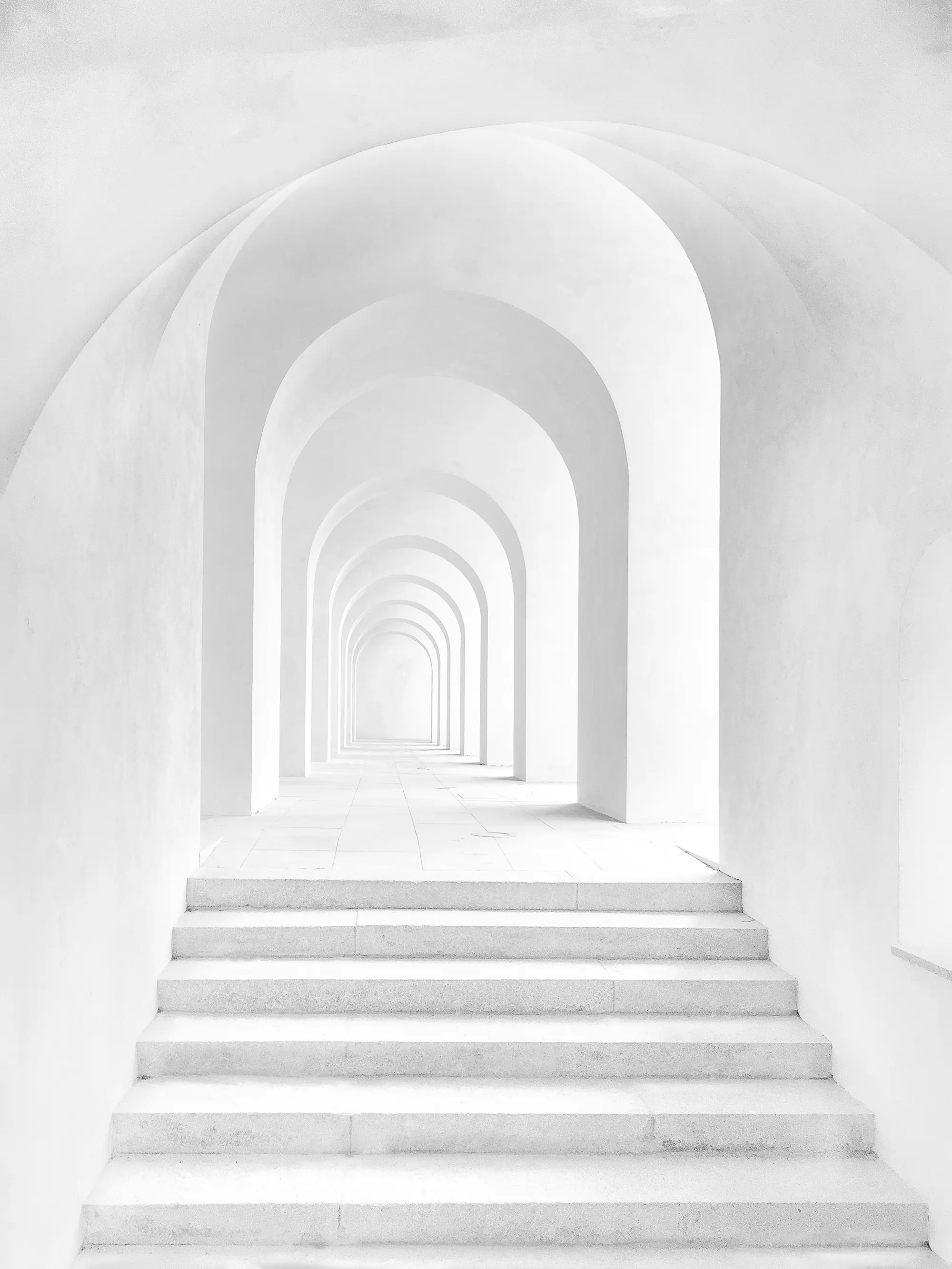 Galería blanca de arcos sucesivos con una escalera
