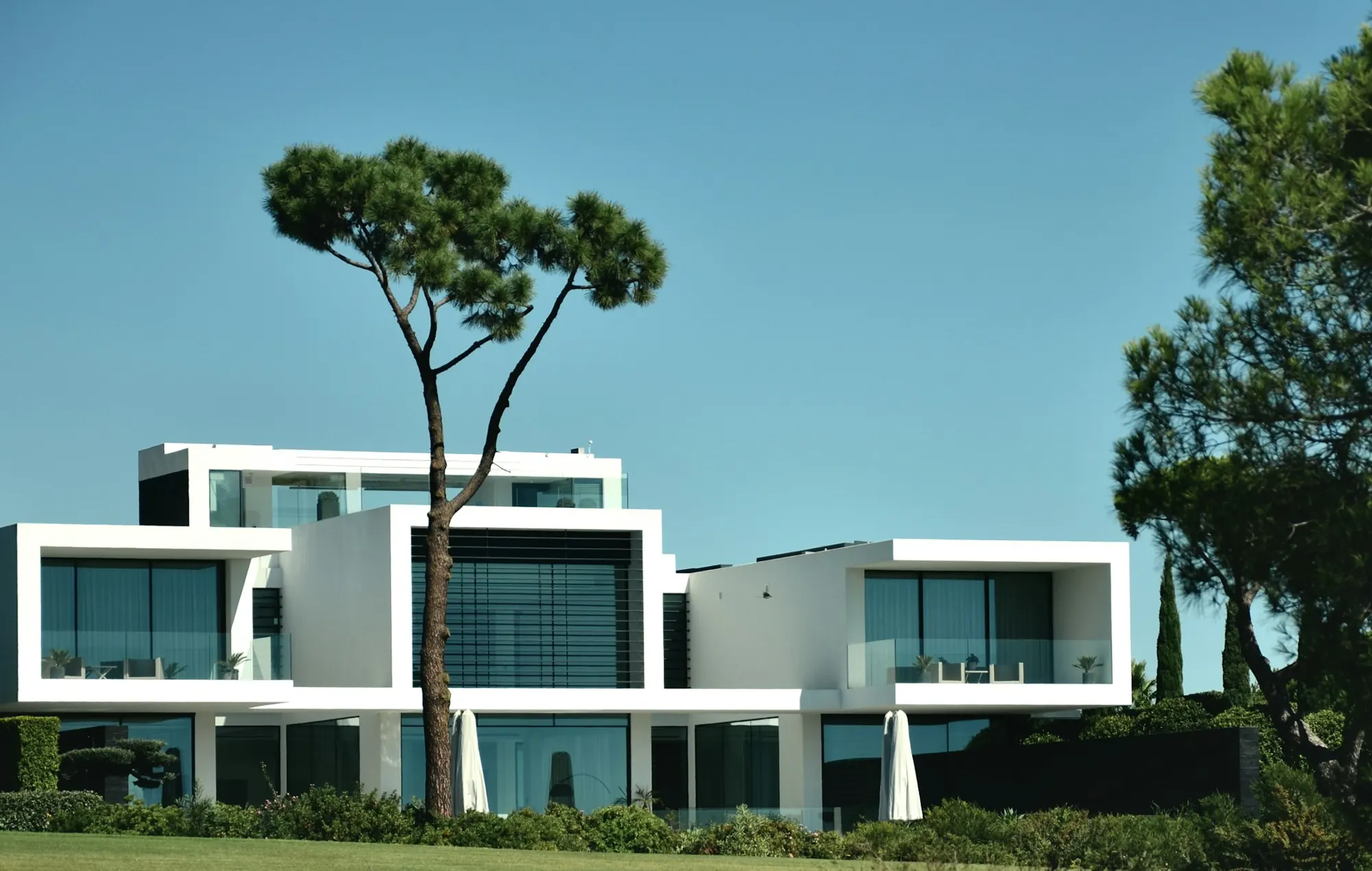 Residencia de volúmenes blancos escalonados entre pinos